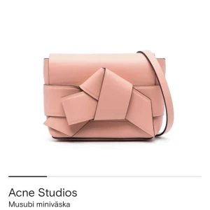 Rosa Musubi miniväska Acne Studios - Supersnygg rosa Musubi miniväska från Acne Studios i skinn med unik knutdetalj framtill och justerbar axelrem. Stilren och modern design med Acne Studios-logga på baksidan. Perfekt storlek för det viktigaste och en riktig statement piece. Helt oanvänd med prislapp! Ni får gärna pruta!
