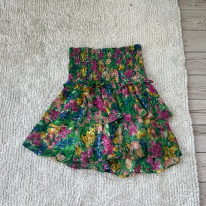 Blommig volangkjol  - Superfin kjol med blommigt mönster i grönt, rosa, gult och blått. Använd en gång, storlek S