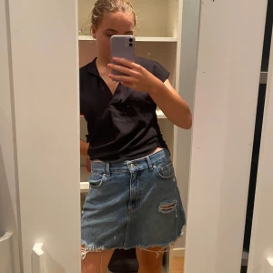 Blå jeanskjol med slitna detaljer - Säljer en jättefin blå jeanskjol med slitna detaljer från NAKD. Säljer p.g.a att jag redan har flera jeanskjolar. Köpt second hand men i väldigt bra skick!🫶🏼