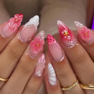 Nageldekorationer med 3D-blommor - Nageldekorationer i rosa och vitt med 3D-blommor, pärlor och små gulddetaljer. Designen har en mix av ombre, fransk spets och snäckmönster. Perfekt för dig som vill ha unika och kreativa naglar med mycket detaljer.