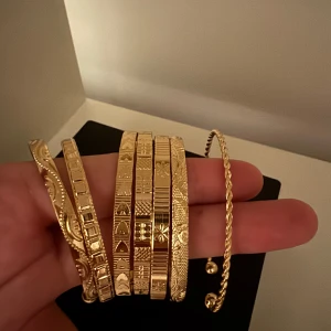 Set med 7 armband i olika mönster - Säljer ett set med flera guldiga armband i olika former och mönster. Några har ingraverade detaljer och geometriska mönster, andra är tvinnade eller har små kulor i ändarna. Perfekt för dig som vill mixa och matcha för en unik look.säljes alla tillsammans
