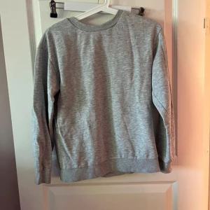 Grå basic sweatshirt BARN 146 - Enkel och stilren grå sweatshirt med rund hals och långa ärmar. Perfekt för en chill look och funkar till det mesta. Mjuk och skön, med ribbade muddar vid ärmslut och nederkant.