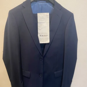 Marinblå kostym köpt för 3090kr säljer för 1500kr - Snygg Marinblå Kostym - Helt Ny, Använd Endast En Gång! Säljer en stilren marinblå kostym i storlek S (Small). Kostymen har använts endast en enda gång vid ett speciellt tillfälle och är i absolut nyskick – inga defekter, fläckar eller slitage. Perfekt för dig som söker en prisvärd men högkvalitativ kostym för bröllop, fest, bal, arbetsintervju eller andra formella evenemang. Detaljer:  * Färg: Klassisk marinblå (mörkblå), lätt att matcha med olika skjortor och accessoarer.  * Storlek: S (Small)
