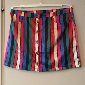 *NY*Färgglad randig kjol från SHEIN XL - Supercool kort kjol från SHEIN i storlek XL med vertikala ränder i blått, rött, grönt, rosa, gult och svart. Kjolen har knappar framtill, två fickor och är gjord i glansig polyester. Perfekt för dig som vill sticka ut med färg och mönster! (Sitter bäst på stl 42) 