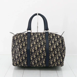 Dior Trotter Speedy 30 - Säljer en klassisk Dior weekendbag med ikoniskt blått monogrammönster på beige canvas. Väskan har svarta skinnhandtag och detaljer, rymlig rektangulär form och dragkedja upptill. Perfekt för dig som vill resa med stil och visa upp en tidlös designerlook.