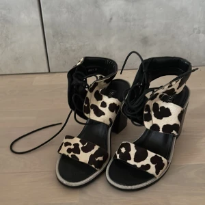 Svarta sandaler med leopardmönster och klack - Unika sandaler från australiensiska Senso, inköpta 2015, med chunky svart klack, snörning runt vristen och coolt komönster i svart och beige. Öppen tå och breda remmar i skinn ger en edgy vibe. 