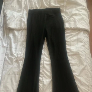 Svarta bootcut byxor med hög midja - Säljer ett par svarta byxor med bootcut-modell och hög midja. De har en stilren look och är perfekta om du gillar en klassisk men trendig vibe. Materialet känns mjukt och stretchigt, vilket gör dem riktigt sköna att ha på sig.