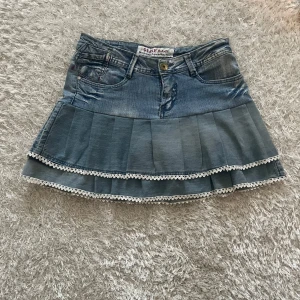 Jeanskjol med volanger och spets - En lågmidjad jeanskjol omsydd från ett par jeans. Midjemått tvärsöver - 40cm  Längd - 38cm