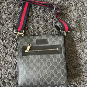 Gucci axelväska med GG-mönster - Snygg axelväska från Gucci i mörkgrått med klassiskt GG-mönster över hela väskan. Jag säljer väskan för att ja har tröttnat på att använda den. 