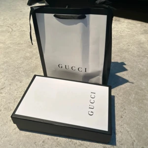 Svart Gucci bälte med GG-mönster och plånbok - Säljer ett svart Gucci bälte i skinn med klassiskt GG-mönster och en stor silverfärgad GG-spänne. Bältet har en stilren och lyxig vibe, perfekt för dig som vill sticka ut med en ikonisk accessoar från Gucci.