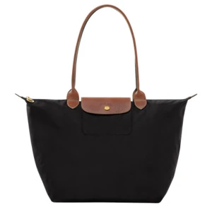 Svart Longchamp Le Pliage axelväska - Klassisk svart Le Pliage axelväska från Longchamp med bruna skinnhandtag och lock. Väskan är rymlig, har guldfärgad knapp och dragkedja. Tillverkad i slitstark polyester med detaljer i skinn. Perfekt för dig som gillar stilren och tidlös design.