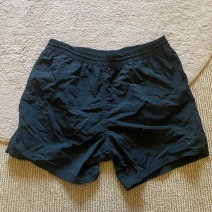 Svarta badbyxor - Svarta shorts från SOC med elastisk midja och vit snörning. Lätt och luftig modell med meshfoder och praktisk bakficka med kardborre. Perfekta för träning eller bad under sommaren🙌🏻