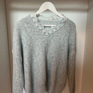 Ljusblå stickad tröja med spetsdetalj - Supermysig ljusblå stickad tröja med v-ringning och snygg spetsdetalj i halsen. Köpte på en marknad i Spanien. 