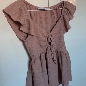 Söt rosa topp med volang🌸 - Supersöt rosa aktig topp💓 V-ringad och en knut framtill. Använd någon enstaka gång och fint skick🤍 tyvärr förstor för mig och därav varför jag säljer den. 