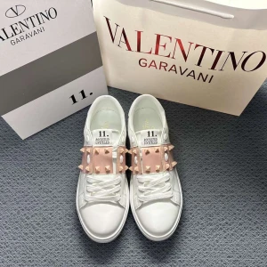 Valentino Garavani skor - Snygga vita Valentino Rockstud sneakers med ljusrosa band och ikoniska nitar i guldton. Skorna har rund tå, platt sula och är tillverkade i skinn. Perfekta för dig som vill sticka ut med en lyxig och edgy vibe.