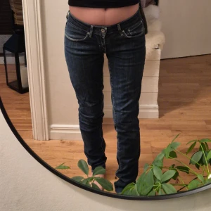 Mörkblå jeans från Levi's - Snygga mörkblå jeans från Levi's med klassisk femficksdesign och knappgylf. De har en låg midja och en skinny passform som framhäver figuren.