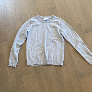 Grå tröja från VILA - Säljer en stilren grå tröja från VILA. Den har en klassisk rund halsringning och långa ärmar. Perfekt för en avslappnad look. Tröjan är mjuk och bekväm, idealisk för kyligare dagar.