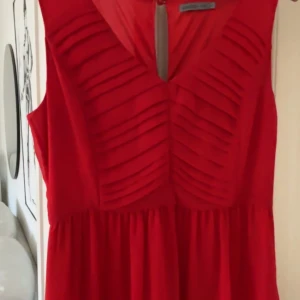 Röd långklänning från Soaked in Luxury - Säljer en elegant röd långklänning från Soaked in Luxury. Klänningen har en v-ringad design med veckade detaljer på bröstet. Perfekt för speciella tillfällen.
