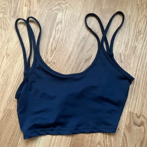 Mörkblå topp med twist i ryggen - Fin kort blå topp i lite sportigare material. Axelbanden är bubbla och den är snurrad i ryggen vilket gör så att den ser mer öppen ut 