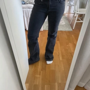 Svarta bootcut jeans - Snygga svarta bootcut jeans med låg midja. Perfekta för en stilren look. De har en klassisk design med fem fickor och knappgylf.