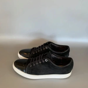 Svarta sneakers från Lanvin - Snygga svarta sneakers från Lanvin med en stilren design. Skorna har en blank tå och snörning framtill. Perfekta för en casual look med en touch av elegans. Endast använda ett fåtal gånger då dom är för stora. Hör av er för fler frågor 🤓 Dustbag tillkommer. Pris kan diskuteras vid snabb affär. Obs inte originalsula därav priset