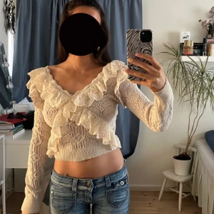 Beige stickad tröja med volangdetaljer - Säljer en söt beige stickad tröja med v-ringning och volangdetaljer. Slutsåld och köpt på Zara, väldigt populär. Hör av er vid frågor🌸