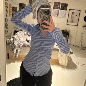 Blå och vit randig skjorta från Zara - Säljer en stilren blå och vit randig skjorta från Zara. Skjortan har en slim passform med långa ärmar och knappar framtill. Perfekt för en chic och klassisk look. Köpt för 500 endast använd 1 gång