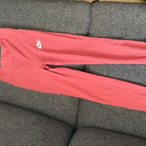 Rosa leggings från Nike - Snygga rosa leggings från Nike med deras ikoniska logga på sidan. De har en tight passform och är tillverkade i ett mjukt och stretchigt material för bästa komfort. Storleken är bar storlek från 156-162.