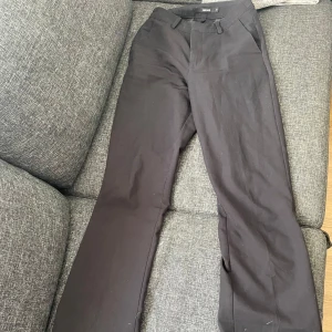 Svarta kostymbyxor - Snygga svarta kostymbyxor med hög midja och raka ben/utslängda byxor. Byxorna har en klassisk design med hällor för bälte och diskreta bakfickor. Använda några gånger. De är hundhår på byxorna för tillfället, men de ska tvättas.