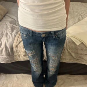 Utsvängda jeans med revor  - Säljer ett par blå jeans med coola revor. Midjemått 33 innerbenslängs 77