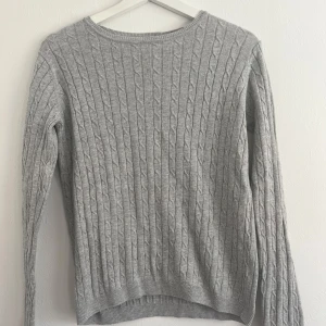 Grå kabelstickad tröja - En ljusgrå kabelstickad tröja med rund halsringning. Tröjan har långa ärmar och ribbade kanter vid ärmslut och nederkant. Den är i fint skick och i storlek 158-164 men mer som en storlek s ✨