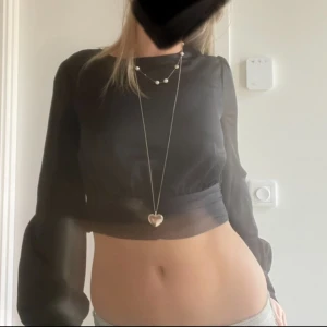 Svart croppad topp/blus med öppen rygg - Snygg svart croppad blus med långa ärmar och öppen rygg. Storlek S och superbra skick! 