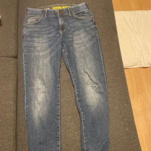 Blå jeans från Lee - Säljer ett par blå jeans från Lee med straight fit och tapered leg. De har en klassisk femficksdesign och en knappgylf. Perfekta för en avslappnad stil. Och inga hål eller fel på dem. Använd dem ungefär 2-4 gånger. 