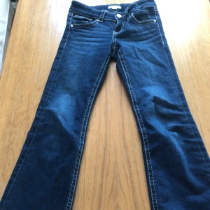 Blå jeans med vida ben från Gina Tricot - Snygga blå jeans från Gina Tricot som är lowest och vida ben. De har dekorativa fickor med knappar bak och är tillverkade i denim. Perfekta för en trendig look! Jag kan hjärna diskutera pris och kan tänka mig nästan vad som helst i pris👍😁