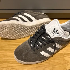 Grå Adidas Gazelle sneakers - Säljer dessa Adidas Gazelle i bra skick! Storlek 38 2/3 passar 38-40. Några små defekter men inget stort! Nypris ca 1099 kr. Mitt pris 399 kr! Pris kan diskuteras vid snabb affär! Om man köper flera varor får man allt mycket billigare! Tveka inte på att höra av er!
