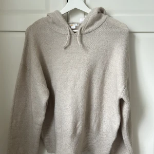 Beige stickad hoodie från Gina Tricot - Mysig beige stickad hoodie från Gina Tricot med huva och dragsko. Tröjan har lång ärm och en avslappnad passform, perfekt för kyliga dagar. Endast använd några enstaka gånger så som ny! 😍