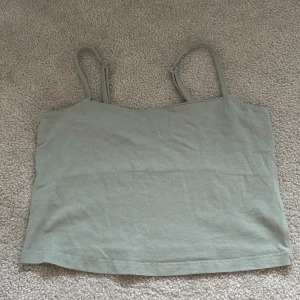 Ljusgrön croppad linnetopp från 157 - Säljer en ljusgrön croppad linnetopp från 157 med smala justerbara axelband. Toppen är tillverkad i mjuk bomull med lite stretch för extra komfort. Perfekt för varma dagar eller som lager under andra plagg.
