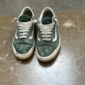 Gröna sneakers från Vans med vit sula - Säljer ett par klassiska gröna Vans sneakers med vit sula och vit sidosnöre. Skorna har rund tå, platt sula och snörning framtill. Perfekta för en avslappnad stil.