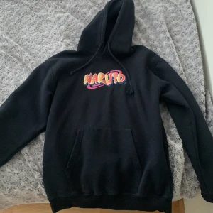Svart Naruto hoodie med Sasuke-tryck - Säljer en svart hoodie med färgglatt Naruto-tryck framtill och stor Sasuke-bild på ryggen. Tröjan har huva och en stor magficka. Perfekt för dig som gillar anime och vill ha en bekväm och snygg tröja.💗🙌🏼