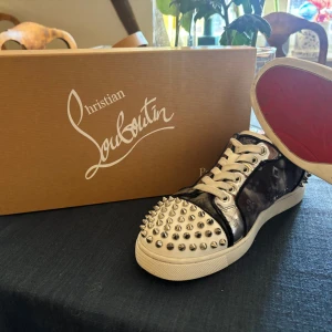 Christian Louboutin sneakers med nitar - Säljer mina fina och unika mörkblå Christian Louboutin sneakers med silvriga nitar på tån och hälen. Har skoboxen, nya nitar och nya sko snörena kvar. Använt få gånger.🩷🩷