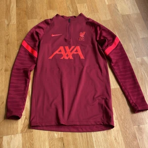 Vinröd Liverpool träningströja från Nike - Säljer en vinröd långärmad träningströja från Nike med Liverpool FC-logga och AXA-tryck på bröstet. Storlek Xs