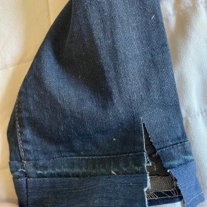 Mörkblå jeansbyxor  - Mörkblå jeansbyxor med klassisk femficksdesign och kontrastsömmar. Byxorna har normal passform och raka ben med liten slits vid benet då jag klippt de själv men funkar perfekt som en detalj. Perfekta för en avslappnad stil. Köpt secondhand, men jag har aldrig använt de.
