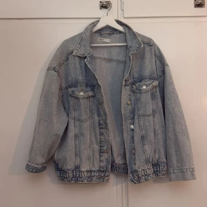 Oversized ljusblå jeansjacka från Gina Tricot - Säljer en oversized ljusblå jeansjacka från Gina Tricot. Jackan har klassisk krage, knappar framtill och två bröstfickor med lock. Resår i midjan ger en avslappnad look. Perfekt att slänga över en hoodie eller t-shirt.