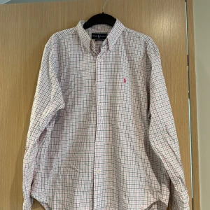 Rutig skjorta från Ralph Lauren - Säljer en klassisk långärmad skjorta från Ralph Lauren. Måttet är ca 72cm långt och bredden är 55cm lång. Storleken är ca L och skicket är bra om ni stryker den kommer den se som ny ut🤩 Nypris cirka 1600kr 