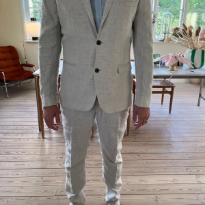 Ljusbeige linnekostym från H&M - Säljer en ljusbeige kostym från H&M i linne med slim fit-passform. Kavajen har två knappar framtill, klassiska slag och fickor med lock. Den är i jätte fint skick, nästan ny och inga tecken på användning. Byxorna är i storlek 48 och kavajen är i storlek 52