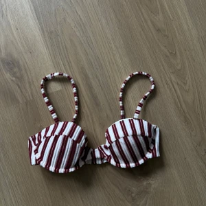 Röd- och vitrandig bikiniöverdel - Säljer en bikiniöverdel med rödvita ränder och vadderade kupor. Axelbanden är smala och mönstrade i samma randiga stil. Aldrig använt!