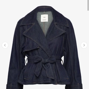 Mörkblå jeansjacka med bälte från MNG - Snygg mörkblå jeansjacka från MNG med bred krage och knytbälte i midjan. Jackan har långa ärmar och markerad midja för en trendig siluett. Perfekt att styla till både jeans och kjol.