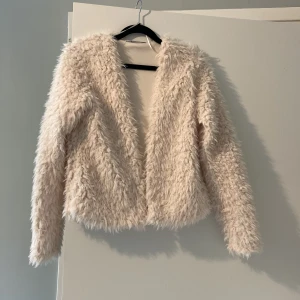 Beige fluffig pälsjacka - Säljer en supermjuk och fluffig beige pälsjacka med lång ärm. Jackan är kortare i modellen och har öppen front utan synliga knappar eller dragkedja. Perfekt för dig som vill sticka ut med en mysig look. Köpare betalar frakten! 💗