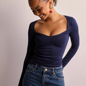 Mörkblå långärmad topp med djup urringning - Säljer en mörkblå långärmad topp med figurnära passform och djup, fyrkantig urringning. Toppen är tillverkad i ett stretchigt material som sitter snyggt på kroppen. Perfekt att styla med jeans eller kjol. Använder sällan och därför väljer jag att sälja den, helt ny och oanvänd inga fläckar eller något. 