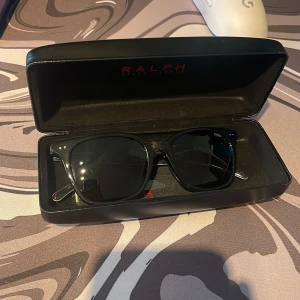 Snygga Ralph lauren solglasögon - Snygga simpla Ralph lauren solglasögon helt oanvända och fortfarande plastade tillbehör. Fick dem i present så finns inget kvitto men nypris ligger runt 1899kr. 